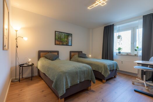 Schlafzimmer 1 mit zwei getrennten Betten und Schreibtisch