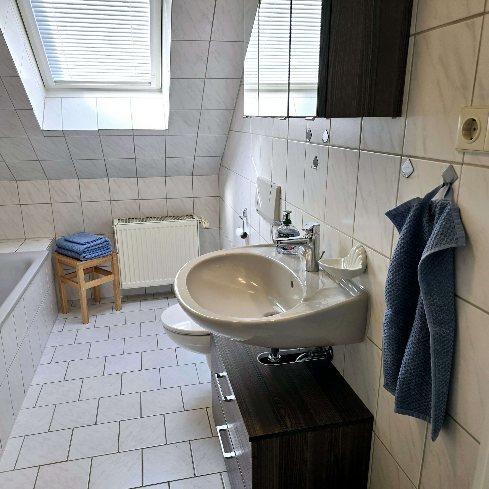 Privates Badezimmer der Dachgeschosswohnung mit Badewanne, Dusche, WC und Handtüchern.