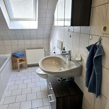 Privates Badezimmer der Dachgeschosswohnung mit Badewanne, Dusche, WC und Handtüchern.