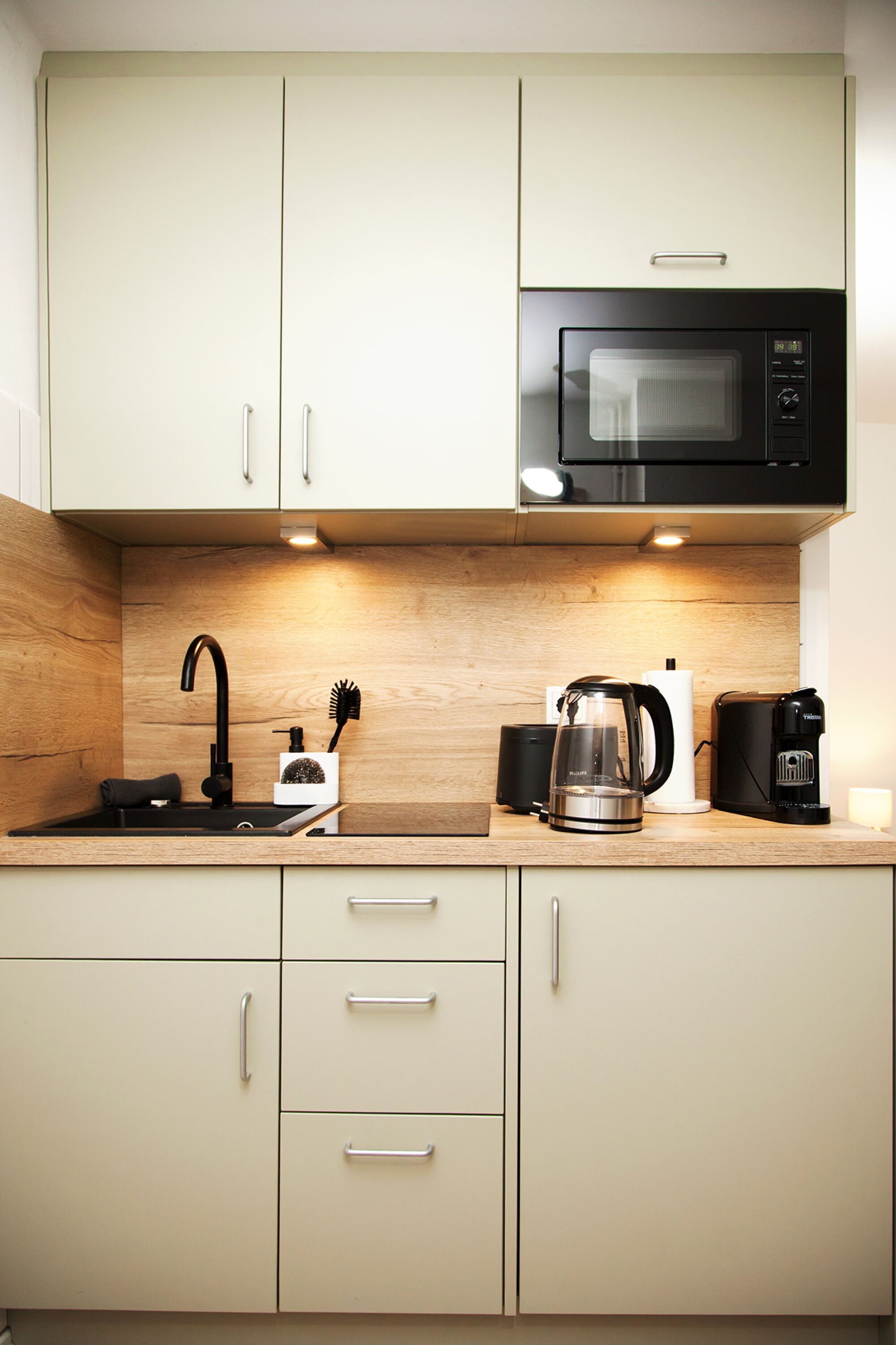 Küche mit Mikrowelle, Herd, Kühlschrank, Wasserkocher, Espressomaschine, Toaster und Kochutensilien