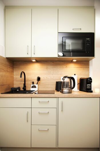 Küche mit Mikrowelle, Herd, Kühlschrank, Wasserkocher, Espressomaschine, Toaster und Kochutensilien