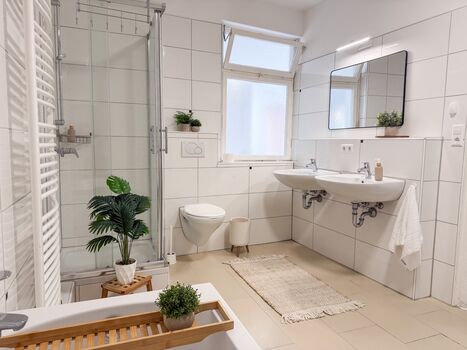 Großzügiges und helles Badezimmer mit Badewanne, Dusche, Handtücher, Toilettenpapier, Seife, Duschgel