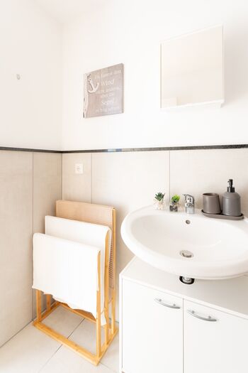 Praktisches Waschbecken mit funktionalem Stauraum und einem stilvollen Handtuchhalter aus Holz – alles für Ihren Komfort. #KomfortBad #Funktional #VonVImmoServiceUG #VollAusgestattet