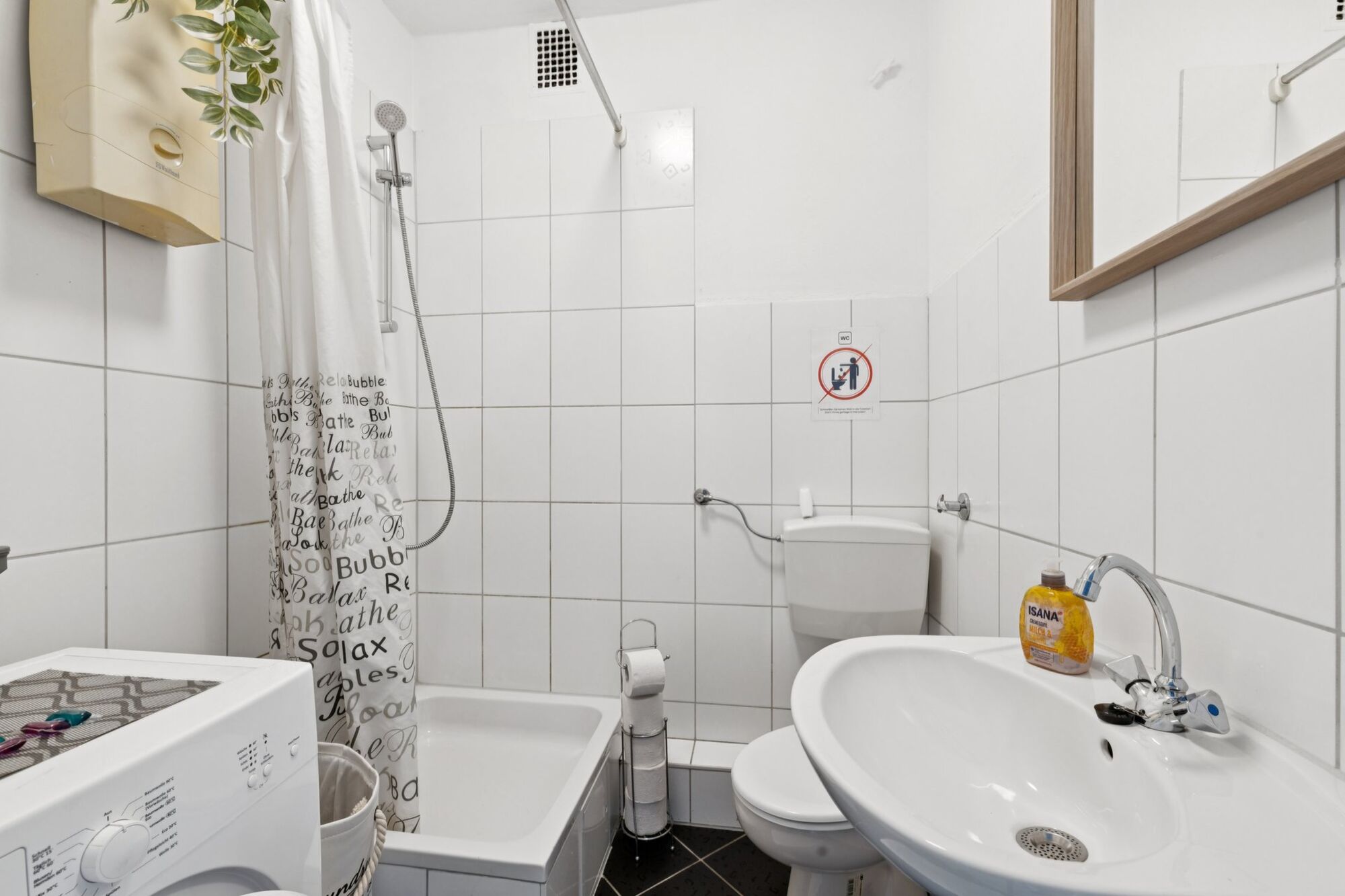 Modernes Badezimmer mit Dusche und Waschmaschine zur kostenlosen Nutzung.
