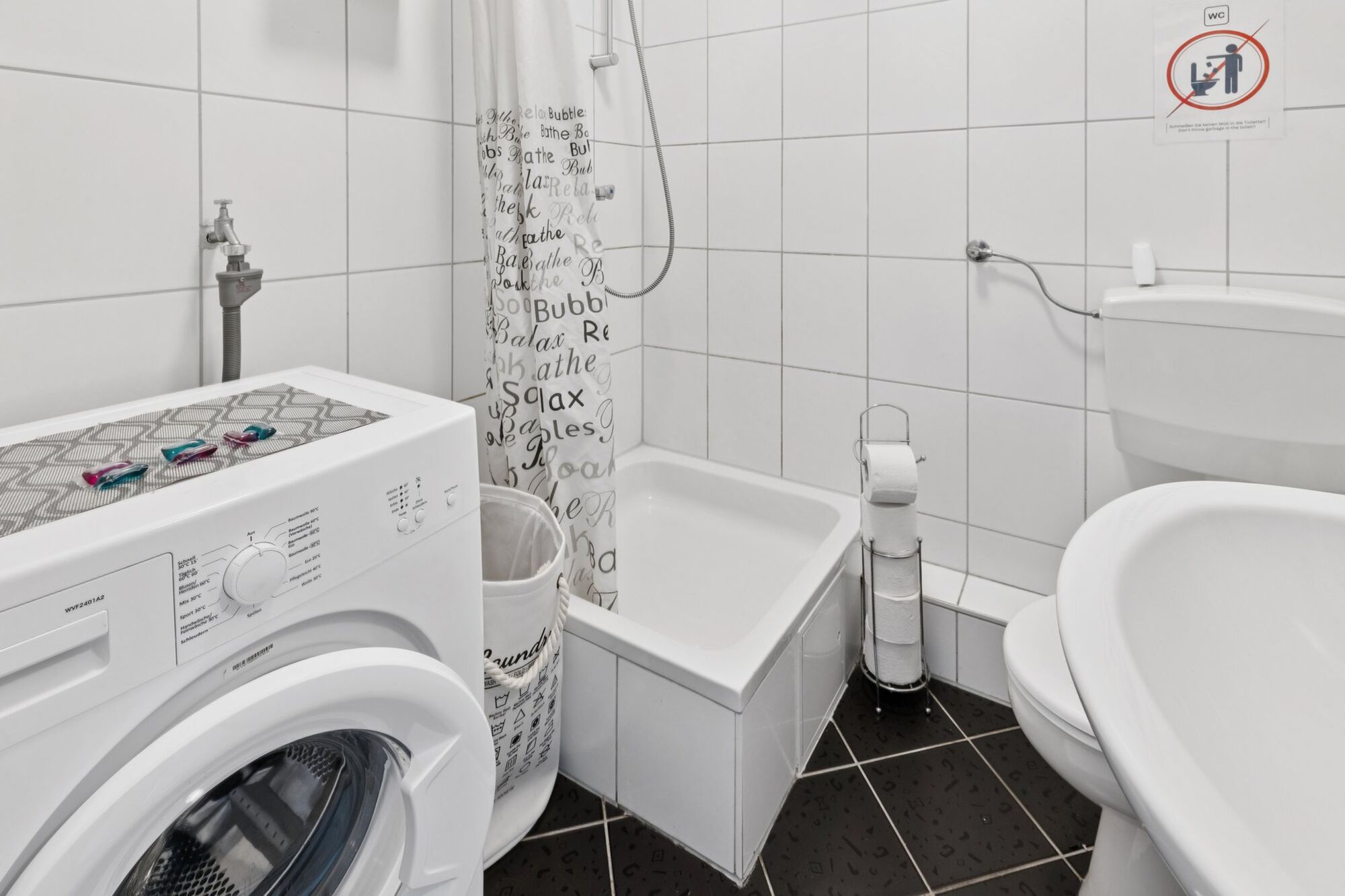 Modernes Badezimmer mit Dusche und Waschmaschine zur kostenlosen Nutzung.