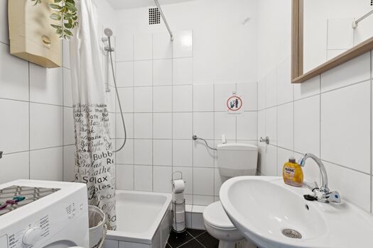 Modernes Badezimmer mit Dusche und Waschmaschine zur kostenlosen Nutzung.