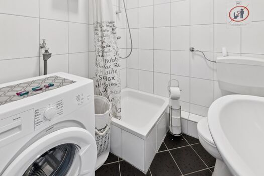 Modernes Badezimmer mit Dusche und Waschmaschine zur kostenlosen Nutzung.