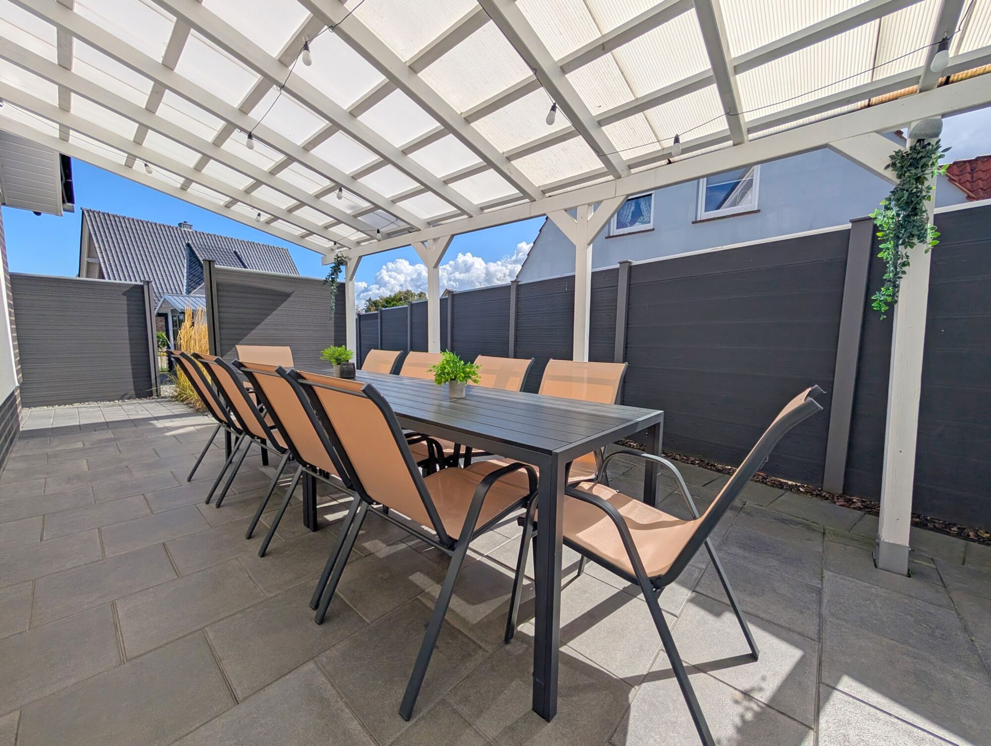 Überdachte Terrasse mit großem Esstisch und Gartenstühle für 10P