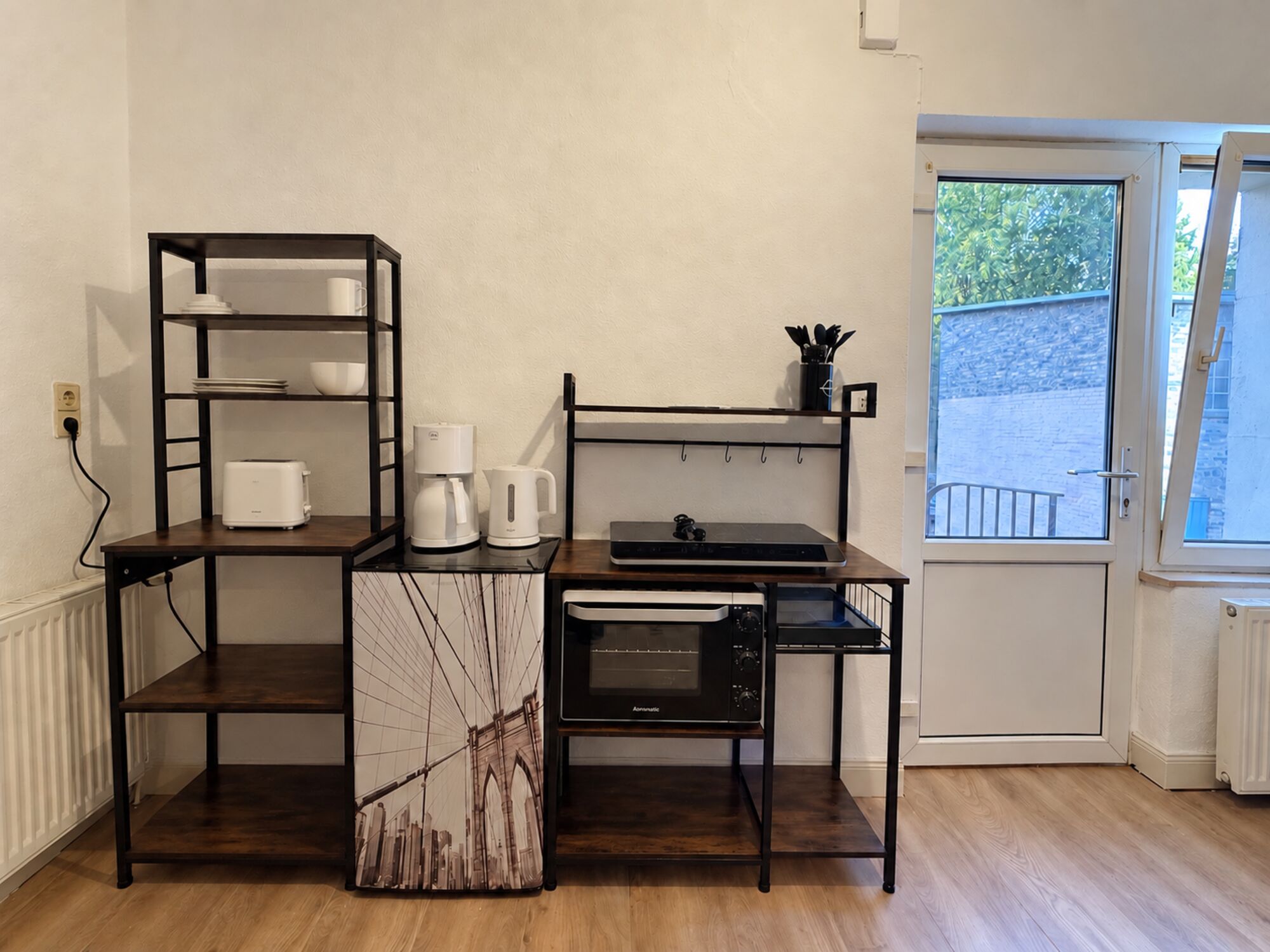 Kühlschrank, Kochgelegenheit mit Backofen und Regale sowie Eingangstür der Wohnung 