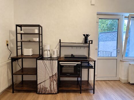 Kühlschrank, Kochgelegenheit mit Backofen und Regale sowie Eingangstür der Wohnung 