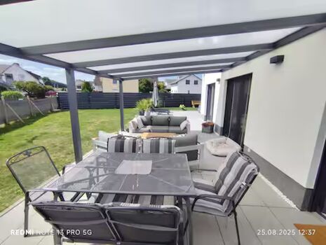 Überdachte Terrasse mit Grill und Sitzgarnitur