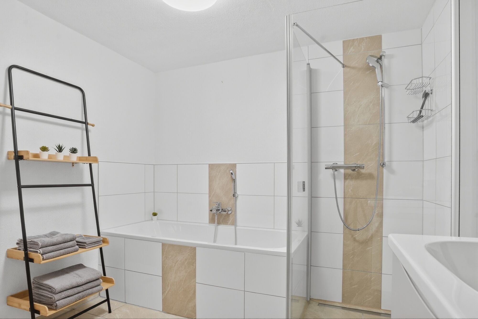 Weißes Badezimmer mit Duschkabine, Badewanne, Handtücher hängen an der Wand.