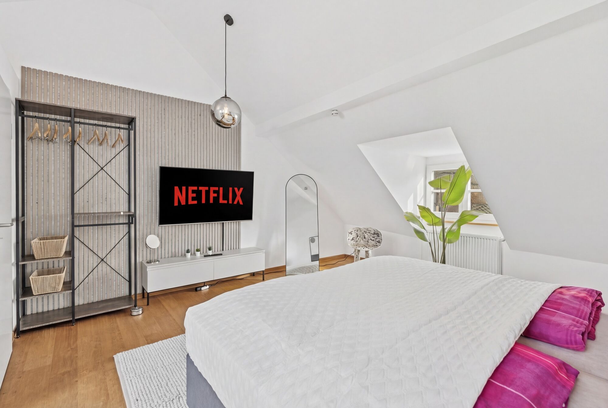 Großes Doppelbett, Smart-TV auf Lamellenverkleidung, offenes Metallregal als Kleidersystem, runde Pe