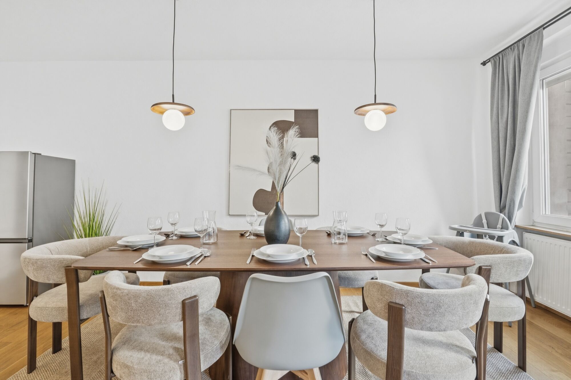 Langer Holztisch mit grau-beigen Polsterstühlen, zwei Pendelleuchten, abstraktes Kunstbild, Hochstuh