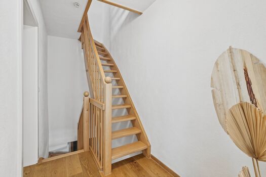 Zwei grüne Bouclé-Sessel um runden Holztisch, großes Frauenporträt als Wandkunst, hohe Zimmerpflanze