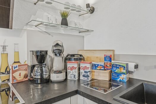 Küchenzeile mit Kaffeemaschine, Mixer, Kaffeepads und verschiedenen Frühstückszutaten.