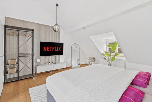 Großes Doppelbett, Smart-TV auf Lamellenverkleidung, offenes Metallregal als Kleidersystem, runde Pe