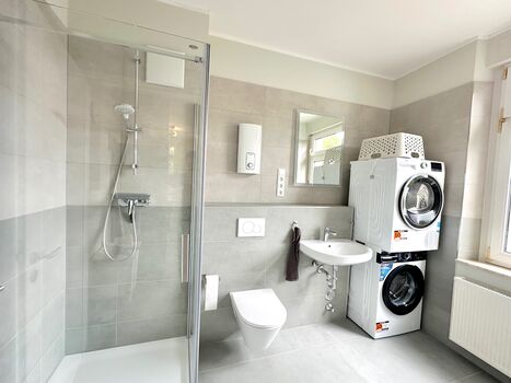 Badezimmer mit Dusche, Waschmaschine und Trockner