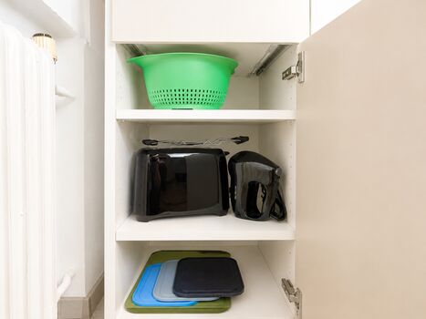 Unterschrank links in der Küche - ausgestattet mit einem Toaster, Handrührgerät, Schneidebrettern und Nudelsieb