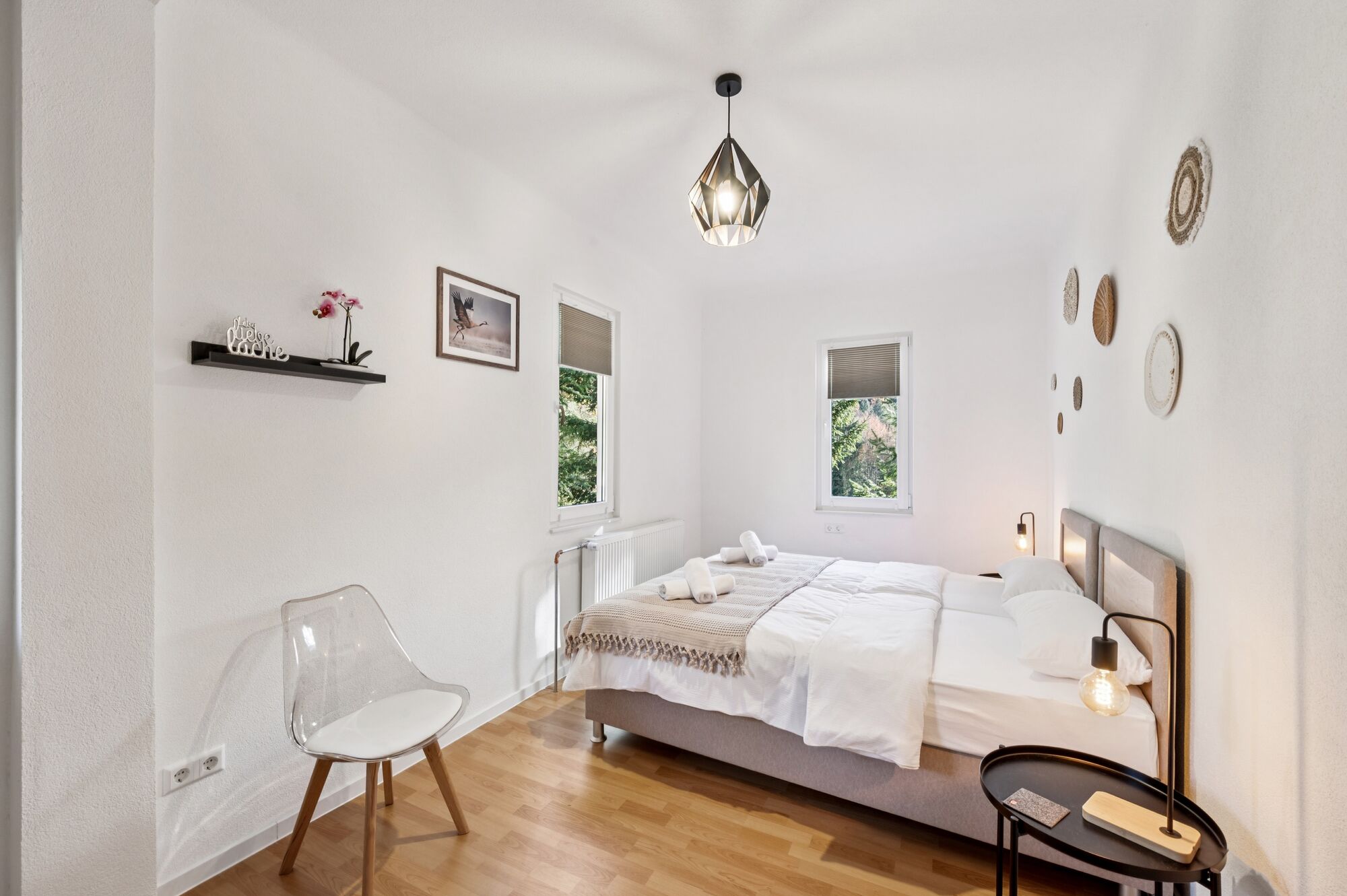 Schlafzimmer 1 mit hochwertigen Boxspringbetten, Nachttischen und einem offenen Kleiderschrank sowie Blick ins Grüne. Die Betten können wahlweise einzeln oder als komfortables Doppelbett gestellt werden.