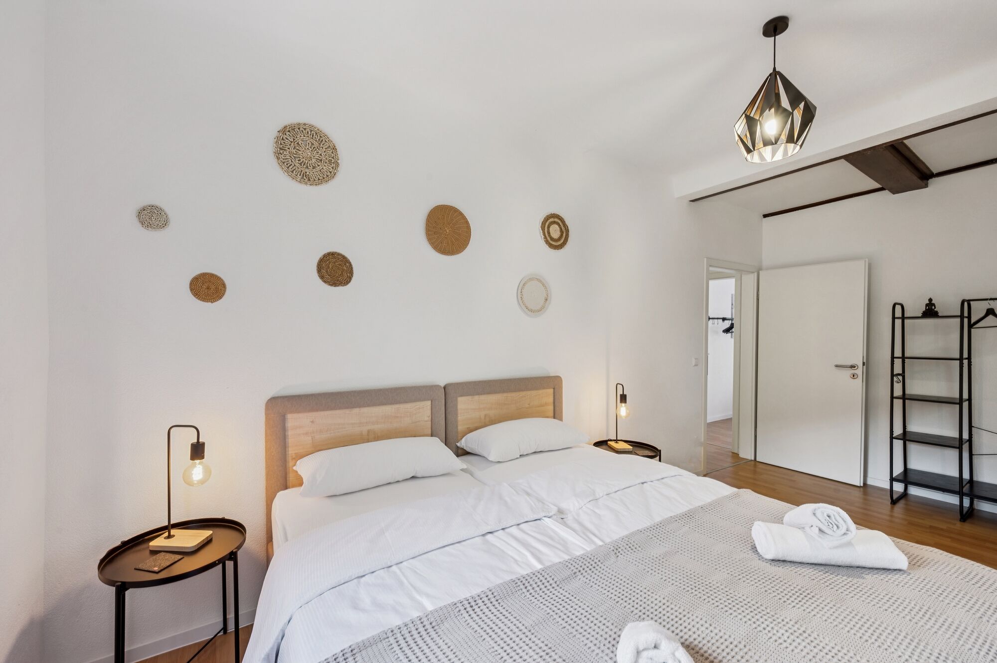 Schlafzimmer 1 mit hochwertigen Boxspringbetten, Nachttischen und einem offenen Kleiderschrank. Die Betten können wahlweise einzeln oder als komfortables Doppelbett gestellt werden.