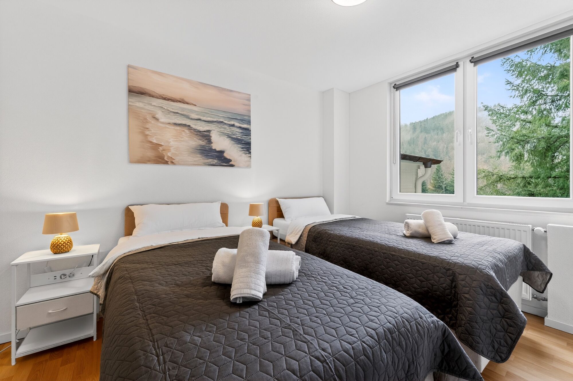 Schlafzimmer 1: Schlafzimmer mit hochwertigen Boxspringbetten, Nachttischen, offenem Kleiderschrank und Smart-TV. Die Betten können flexibel als Einzelbetten oder als komfortables Doppelbett gestellt werden.