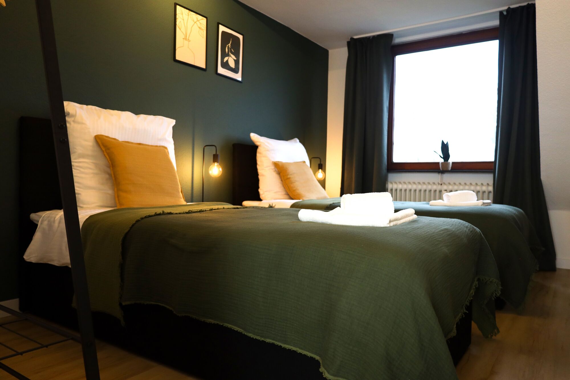 Schlafzimmer 2 - Twin-Schlafzimmer mit zwei Einzelbetten, hochwertiger Bettwäsche, TV, Nachttischlampen und ruhigen Grüntönen.