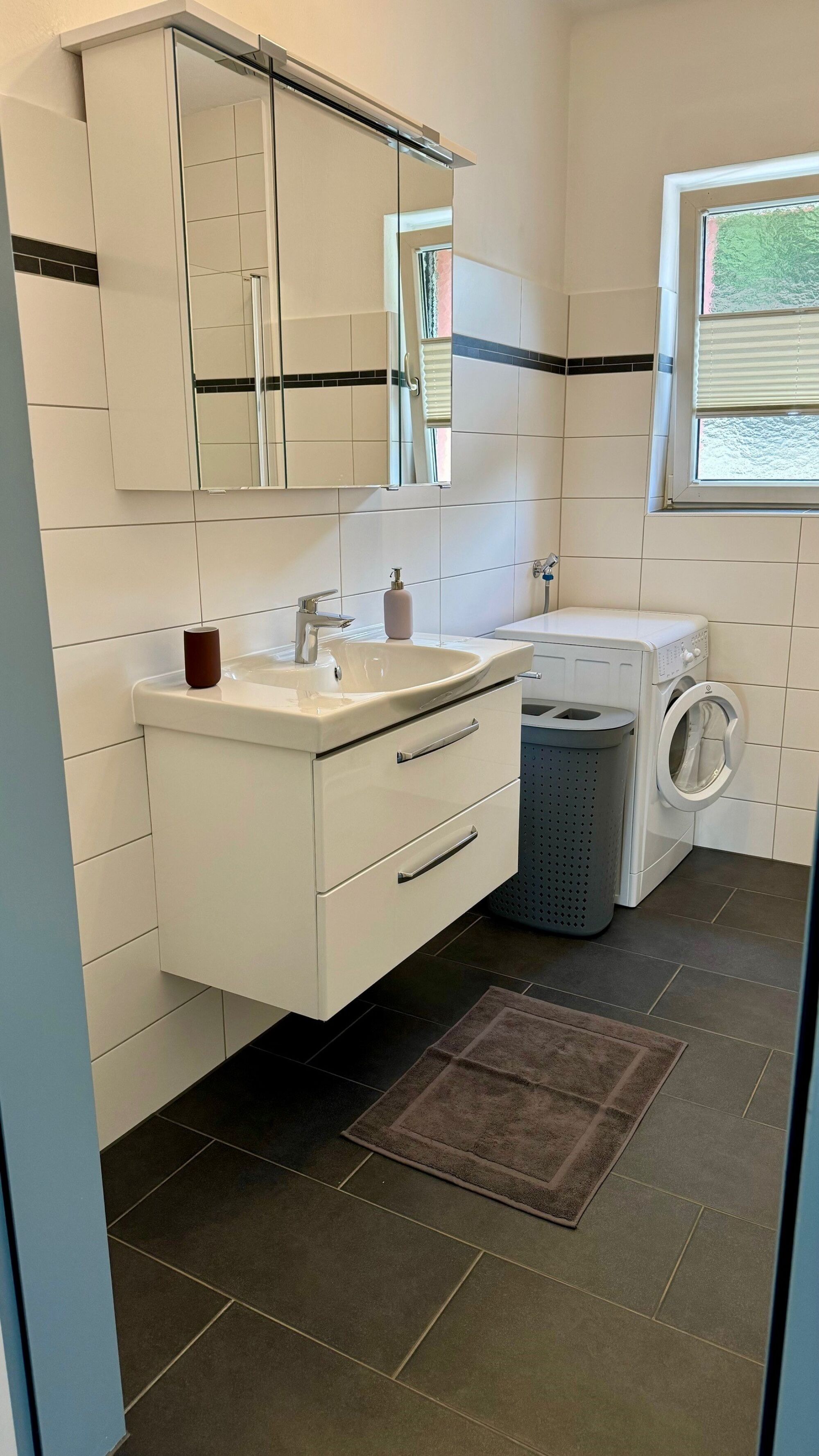 Großes Badezimmer mit Dusche, Waschbecken und Waschmaschine