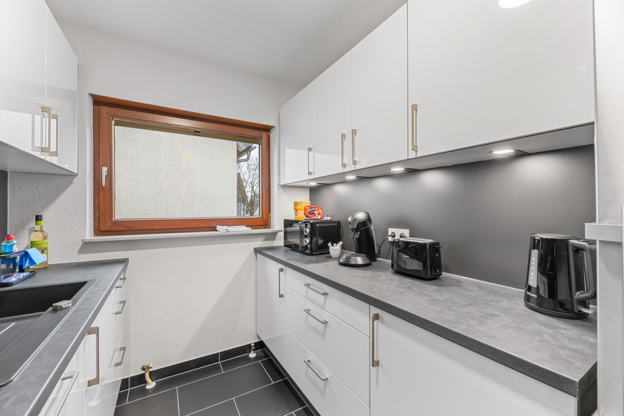 Voll ausgestattete Küche mit Mikrowelle, Kaffeemaschine, Wasserkocher und Toaster.