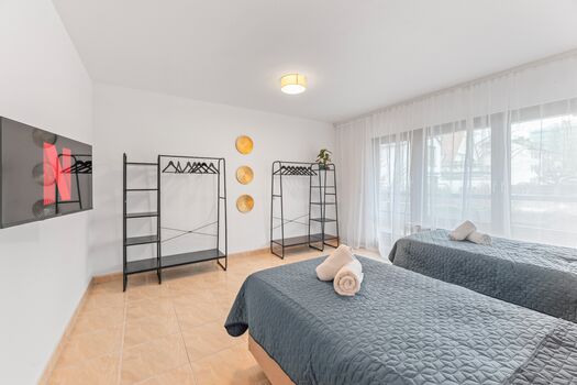 Schlafzimmer 1 mit zwei Boxspringbetten, Smart-TV und Kleiderständern.