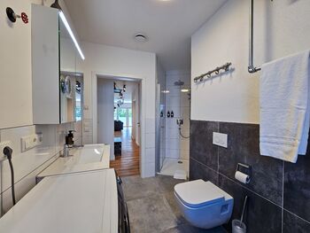 Badezimmer mit Dusche, WC, Waschtrockner & Badewanne