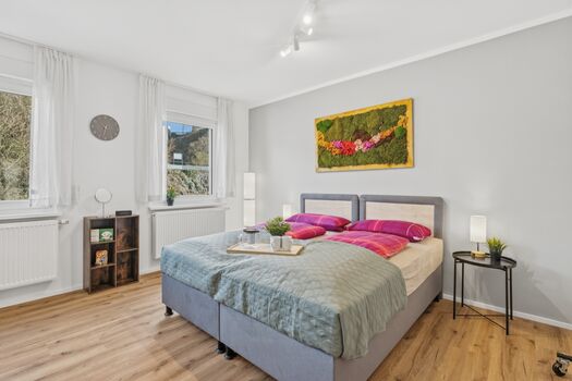 Zwei Einzelbetten zusammengestellt, großes Fenster mit Grünblick, buntes Moosgemälde, heller Holzbod