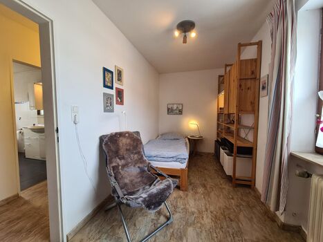 Kleines Schlafzimmer mit einem Einzelbett und Arbeitsbereich, Sessel