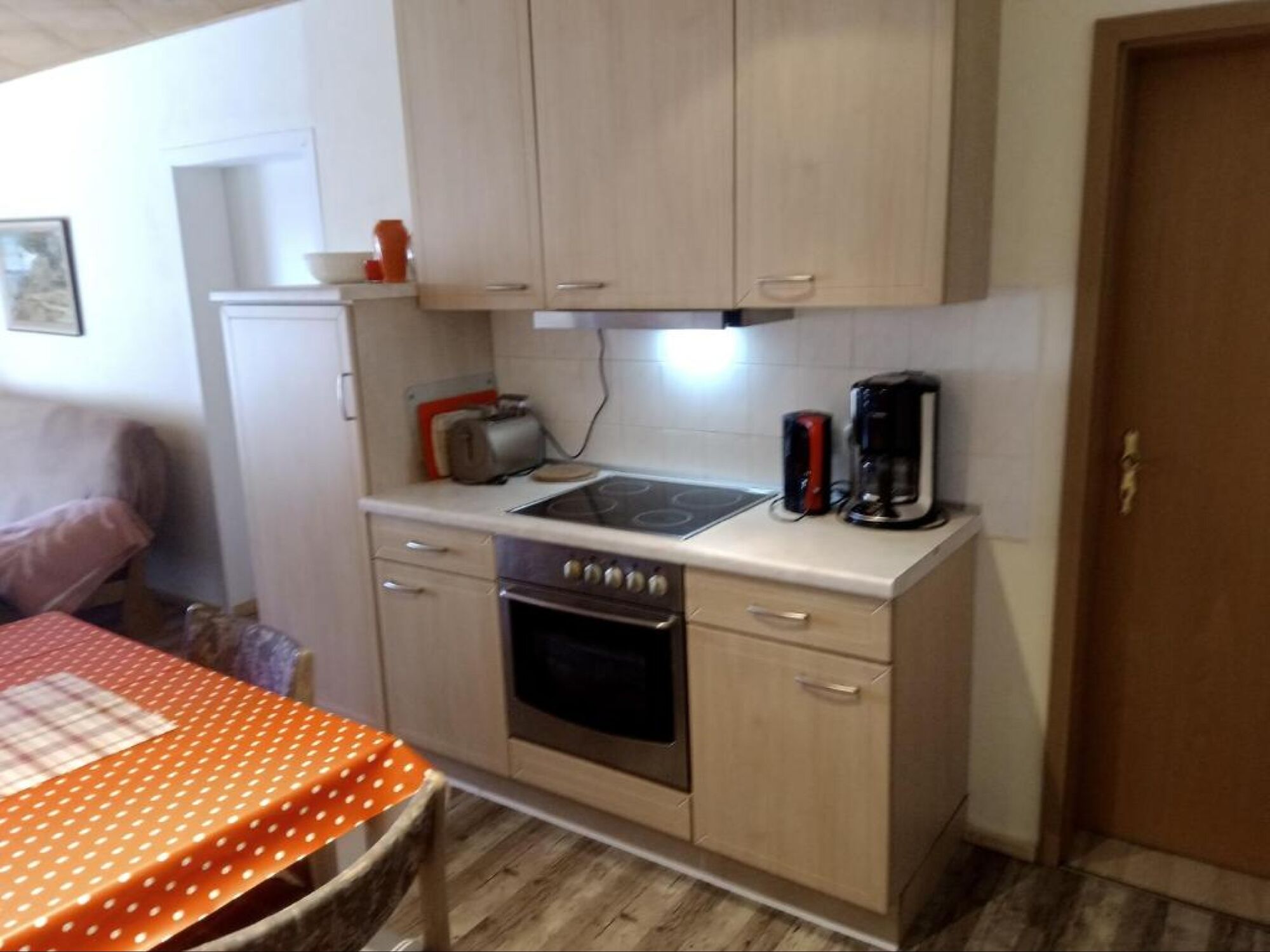 Küche mit Ceranherd und Backofen, Kühlschrank und Gefrierschrank, Geschirrspüler, Toaster, Kaffeemaschine und Wasserkocher